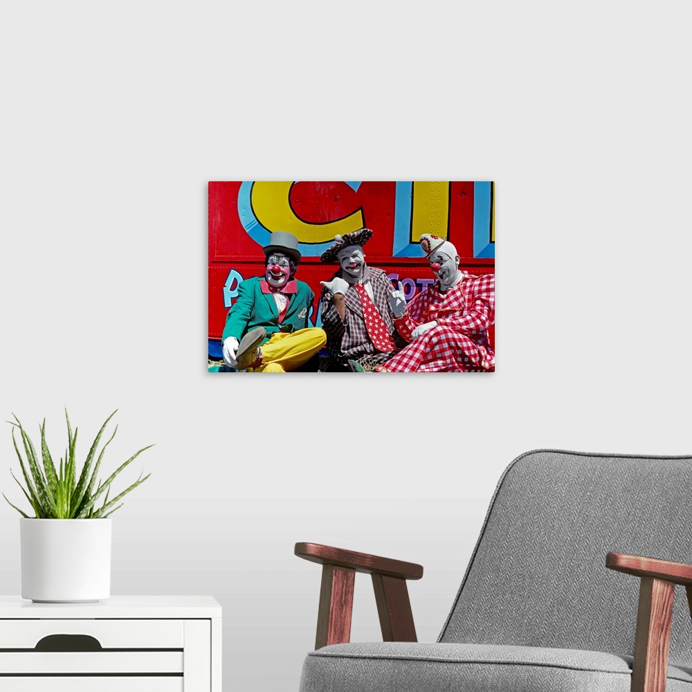 A modern room featuring 1970s Three Circus Clowns In Colorful Costumes And Hats Looking At Camera Two Picking On One.