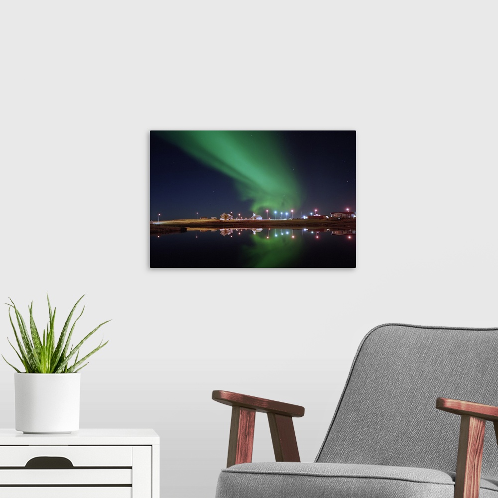 A modern room featuring Aurora Borealis over a town, Njardvik, Iceland