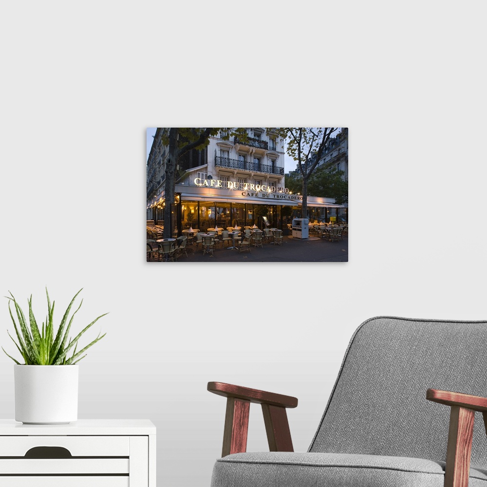 A modern room featuring A photograph at dusk of the Cafe Du Trocadero in Paris, France.