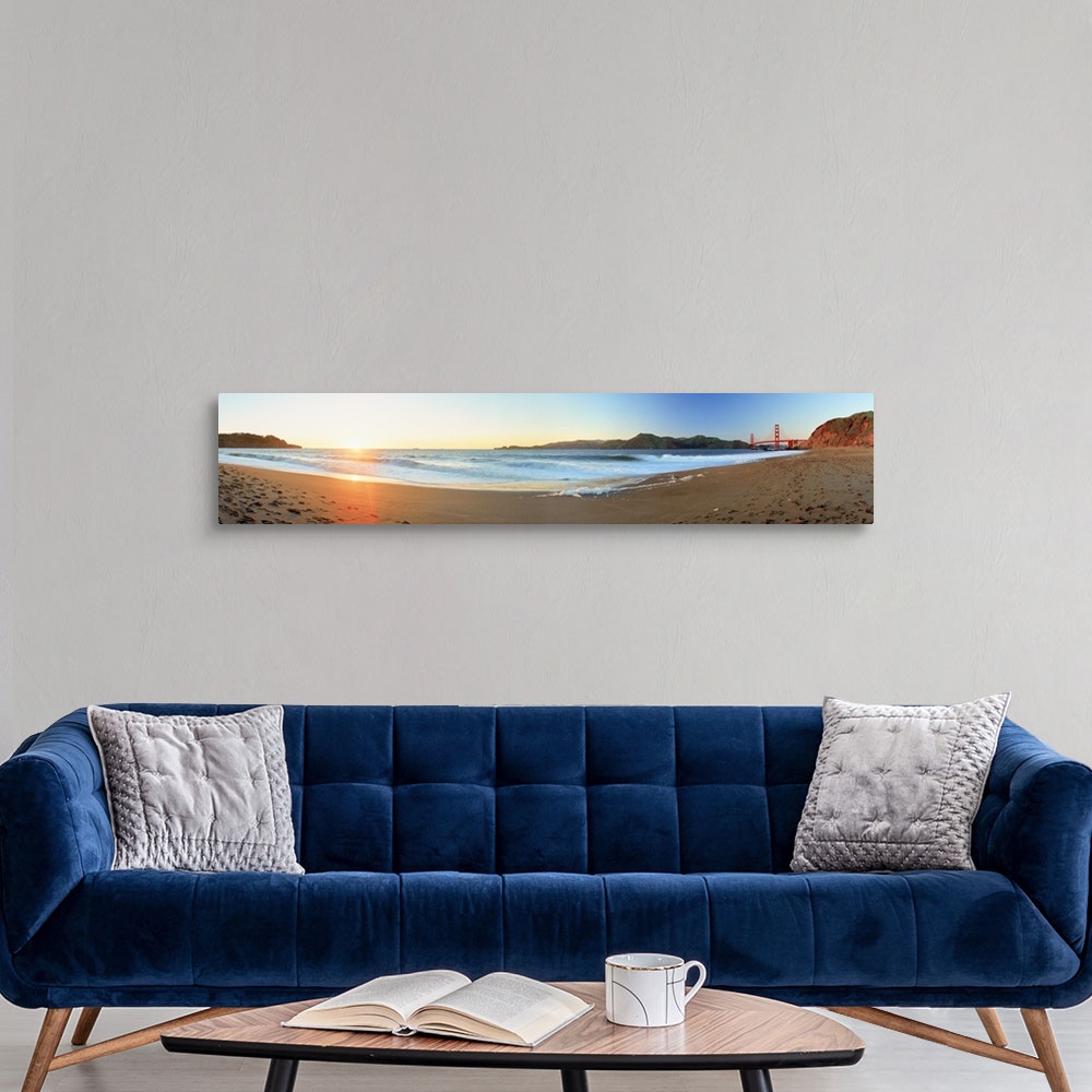 A modern room featuring Long panoramic photo of a beach with the golden gate bride on the far right and the setting sun o...
