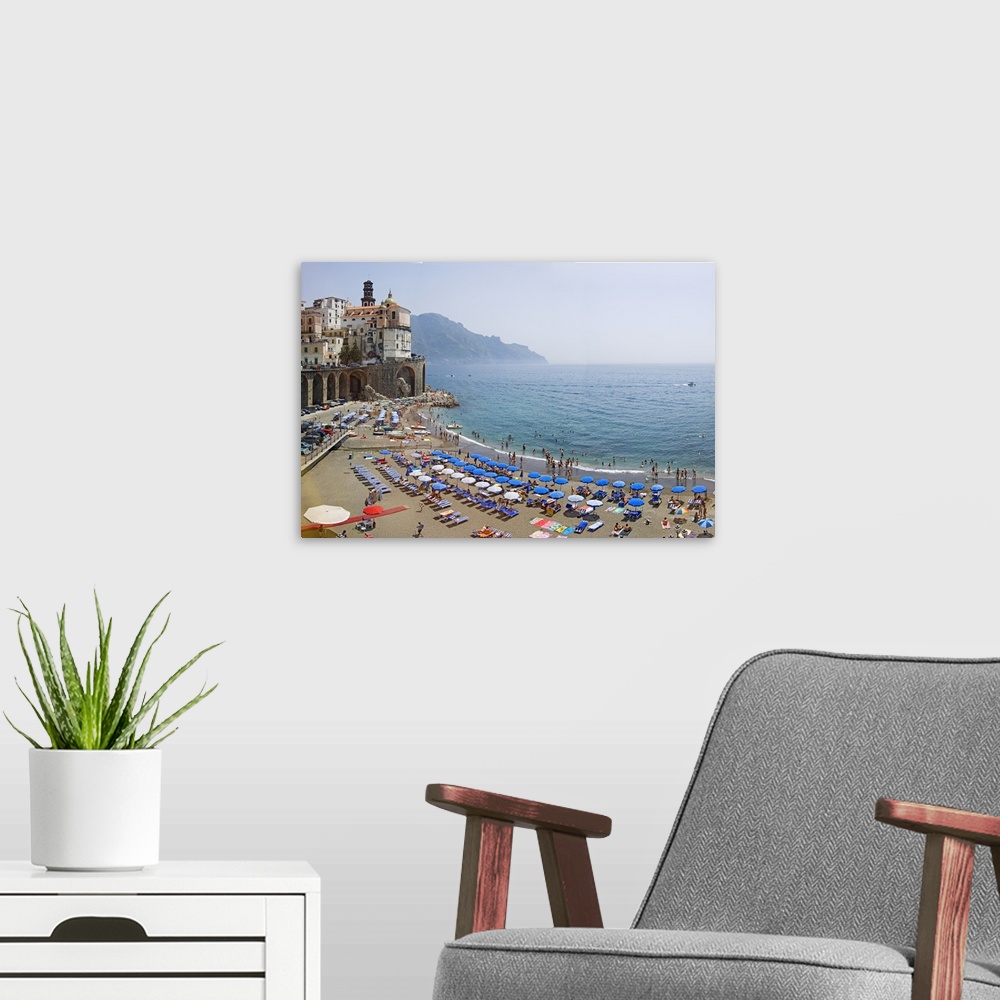 A modern room featuring Summer scene on the beach with lots of parasols and swimmers, and historic buildings on the edge ...