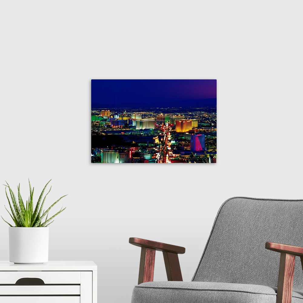 A modern room featuring View from above of the Las Vegas strip its neon lights glowing in the night sky in a horizontal p...