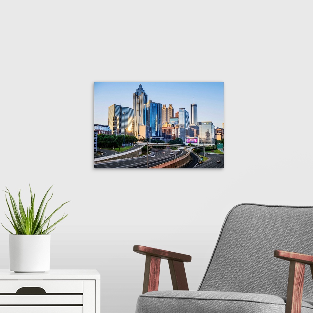 A modern room featuring Morning sunlight reaching the skyscrapers of Atlanta, Georgia, see from the freeway.