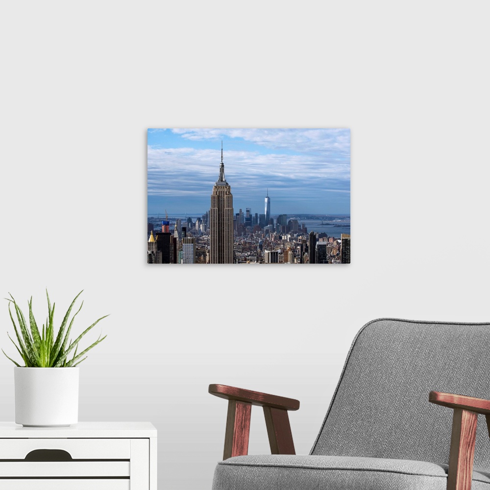 A modern room featuring The Empire State Building rising above the New York City skyscrapers, with the One World Trade Ce...