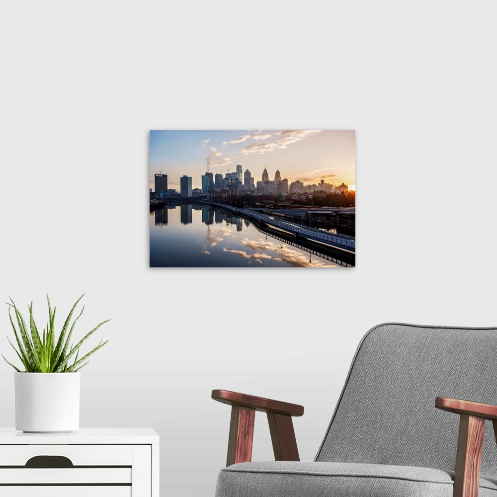 A modern room featuring The sun rises above Philadelphia's city skyline with the sky reflecting on the Delaware river.
