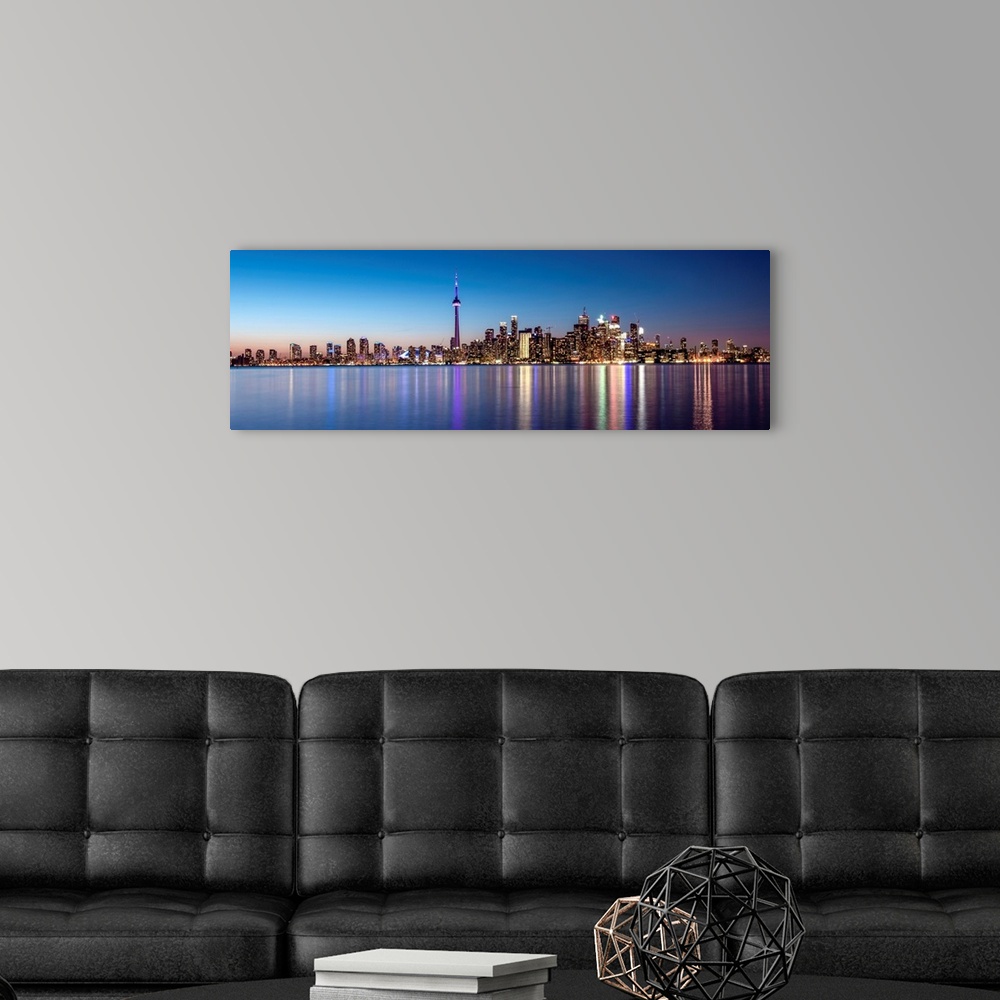 A modern room featuring Panoramic photo of the Toronto city skyline with lights reflected in the water at night.