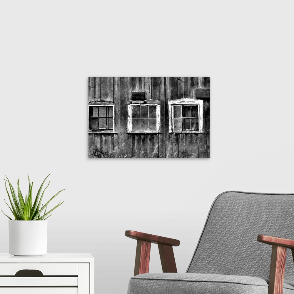 A modern room featuring Black and white photograph of three white framed window on an aging barn.