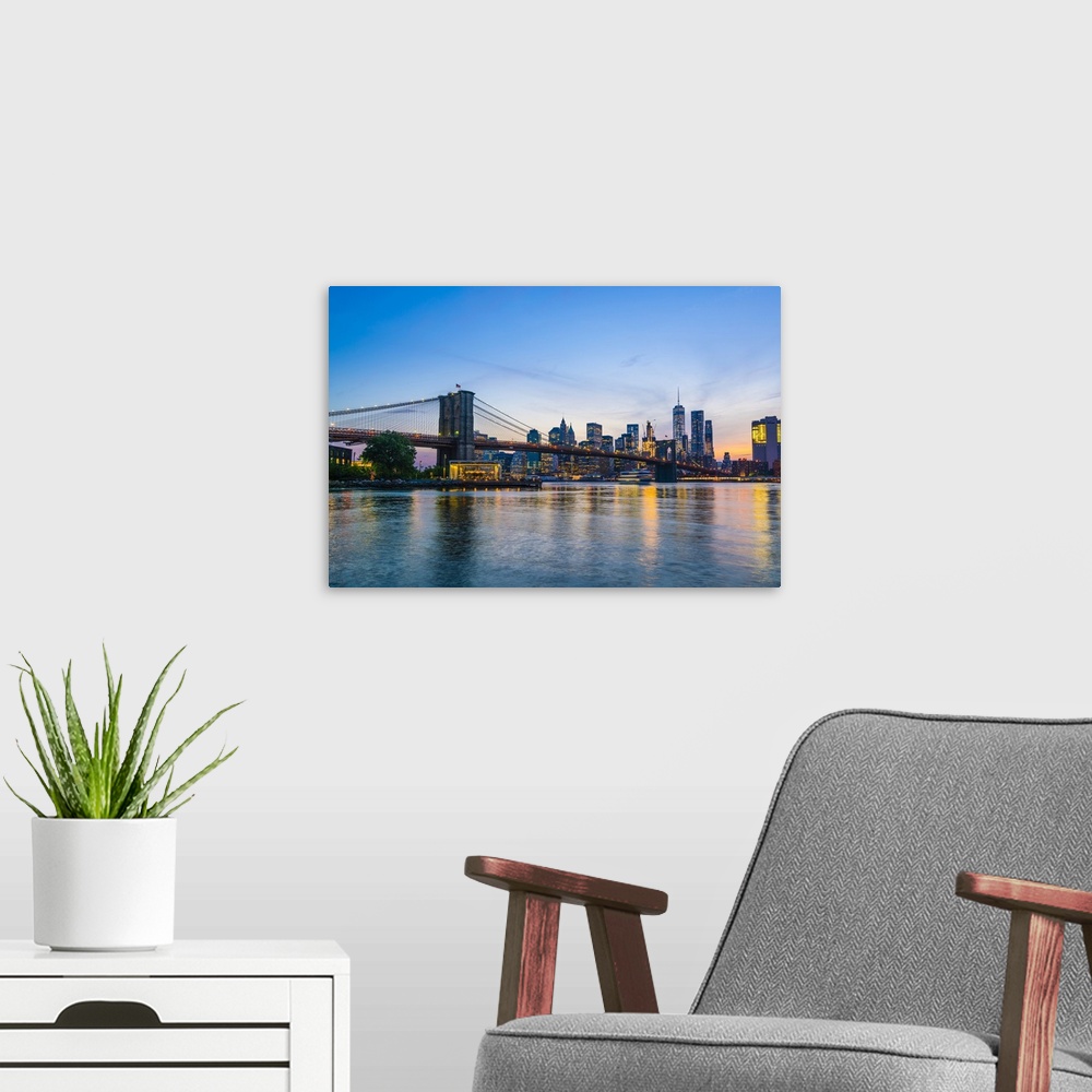 A modern room featuring Brooklyn Bridge and Manhattan skyline at dusk, viewed from the East River, New York City