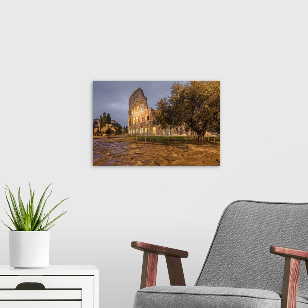 A modern room featuring Dusk lights on the Colosseum, the old Flavian Amphitheatre, and symbol of the city, Rome, Lazio, ...