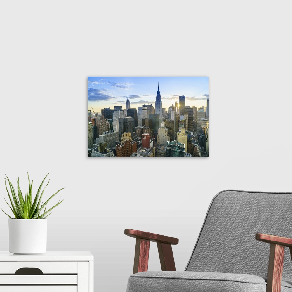 A modern room featuring Manhattan skyline, Empire State Building and Chrysler Building at sunset, New York City, United S...
