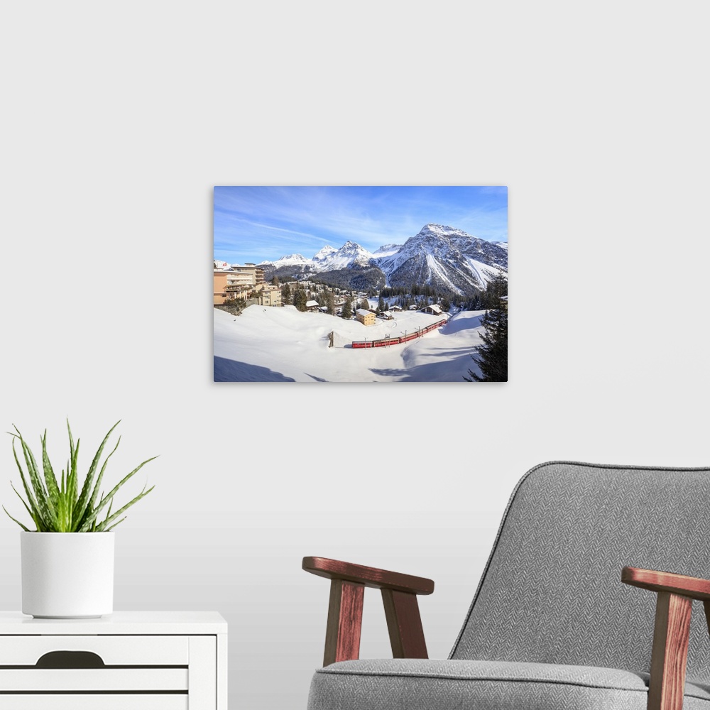 A modern room featuring Red train of Rhaetian Railway passes in the snowy landscape of Arosa, district of Plessur, Canton...