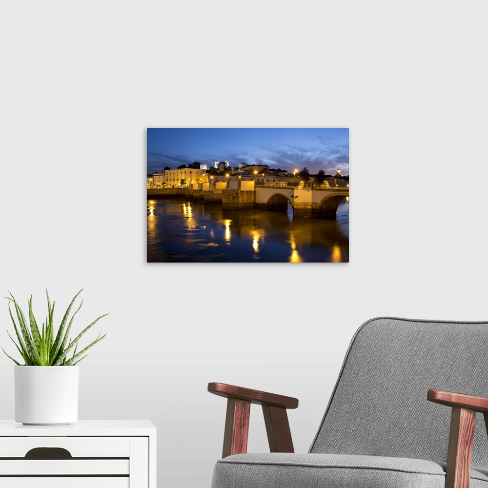 A modern room featuring Seven arched Roman bridge and town on the Rio Gilao river at night, Tavira, Algarve, Portugal