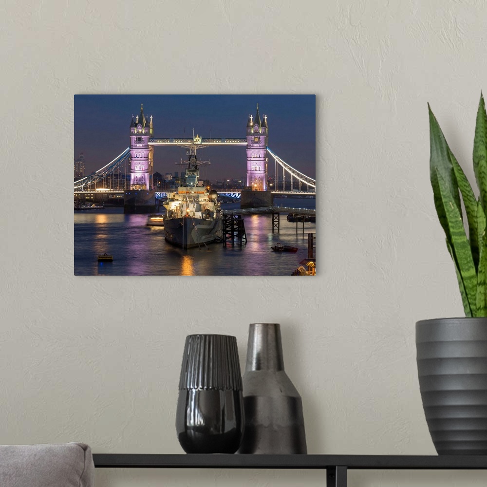 A modern room featuring Tower Bridge and HMS Belfast on the River Thames at dusk, London, England