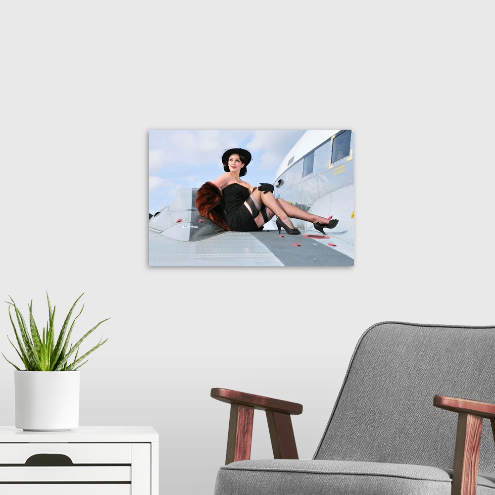 A modern room featuring Glamorous woman in 1940's style attire sitting on a vintage aircraft.