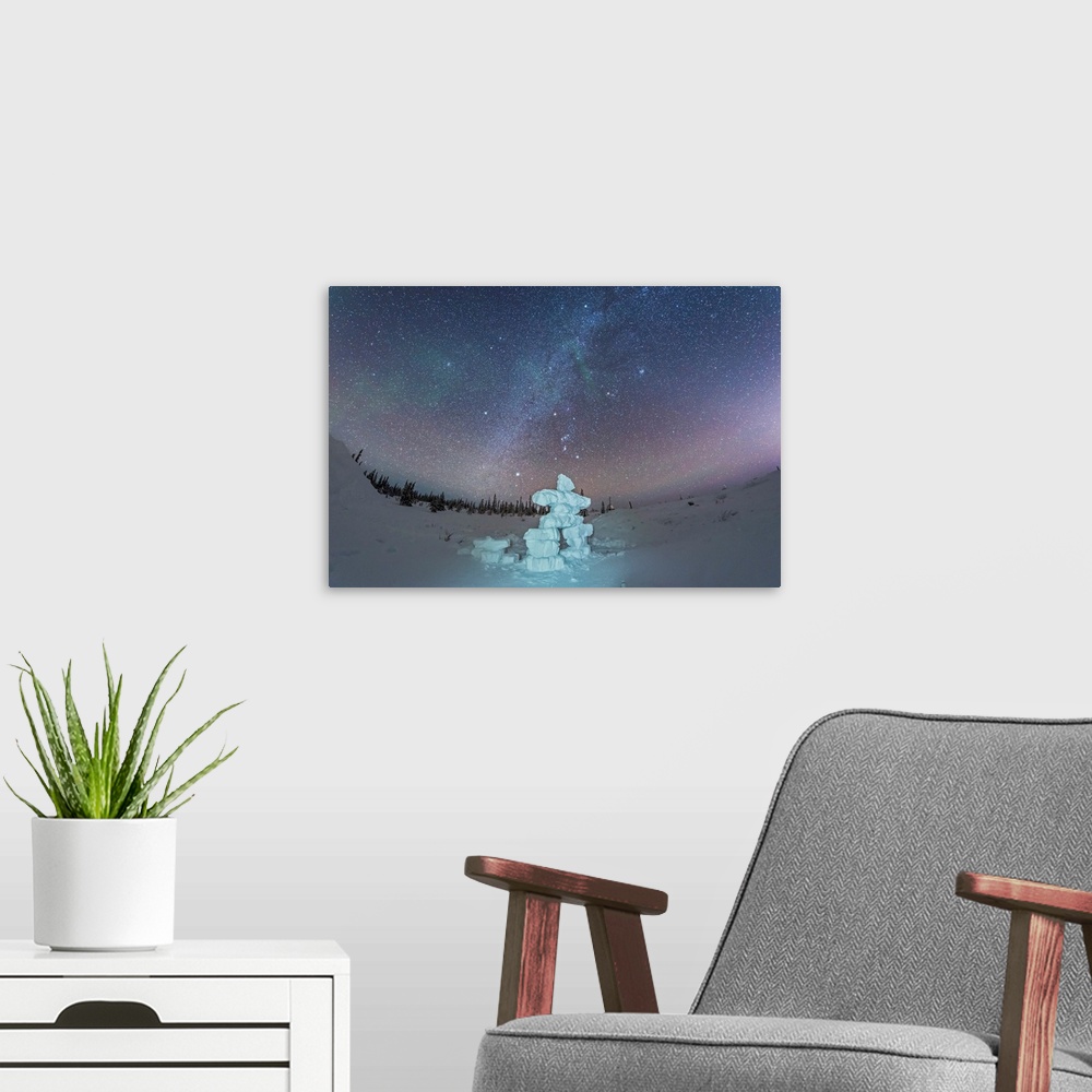 A modern room featuring Milky Way and winter stars over a mock-up inukshuk figure made of snow, Canada.