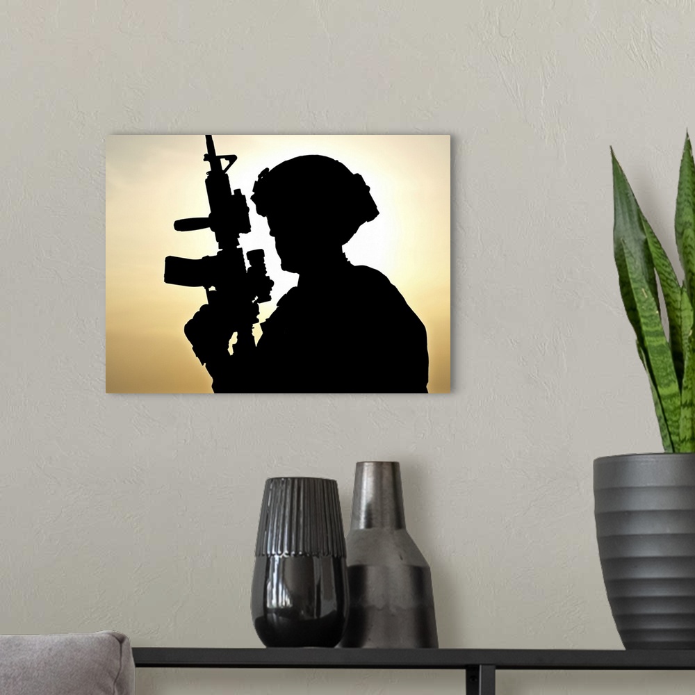A modern room featuring Silhouette of young soldier against the sun.