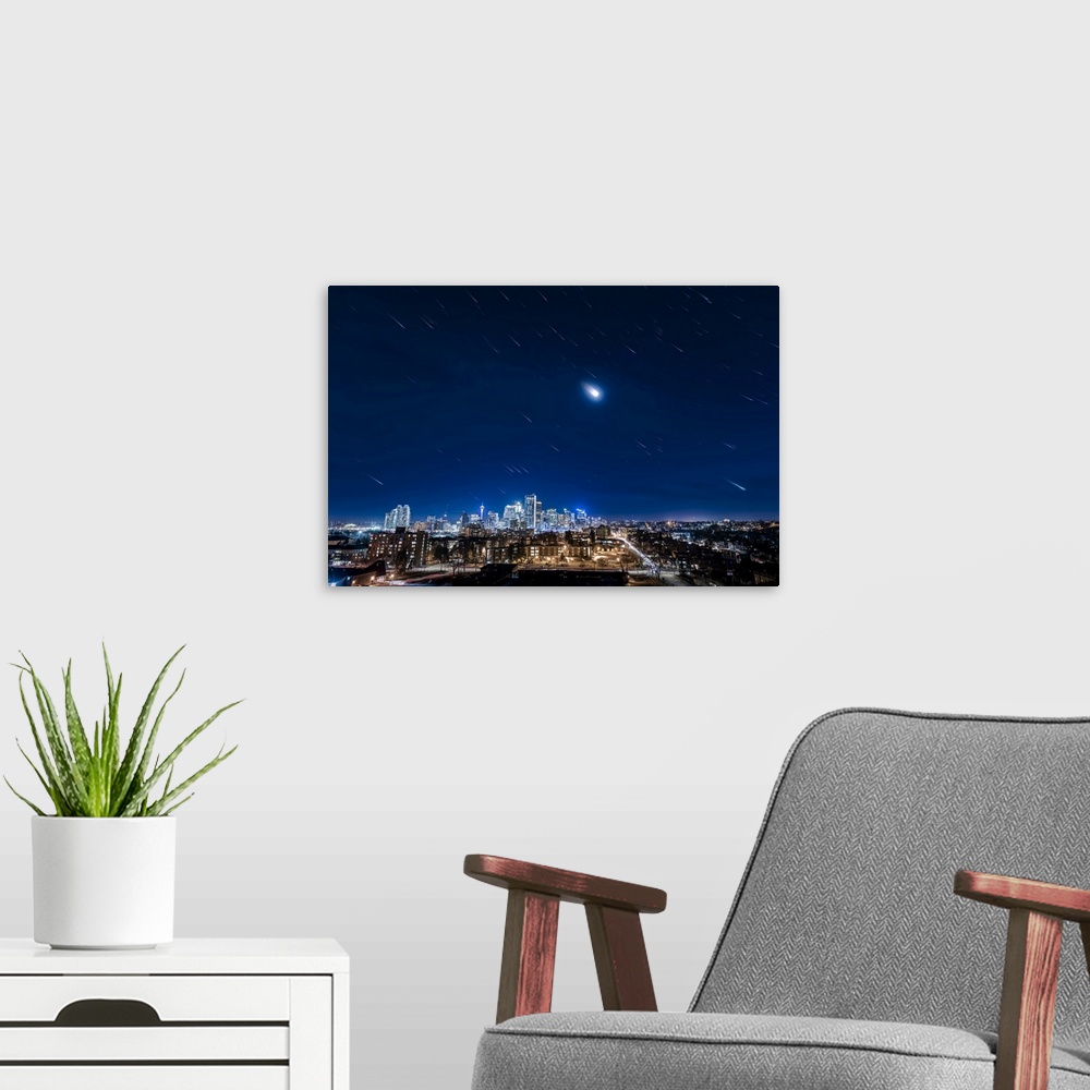 A modern room featuring Star trails of Orion, the moon, and the stars of winter over downtown Calgary, Canada.