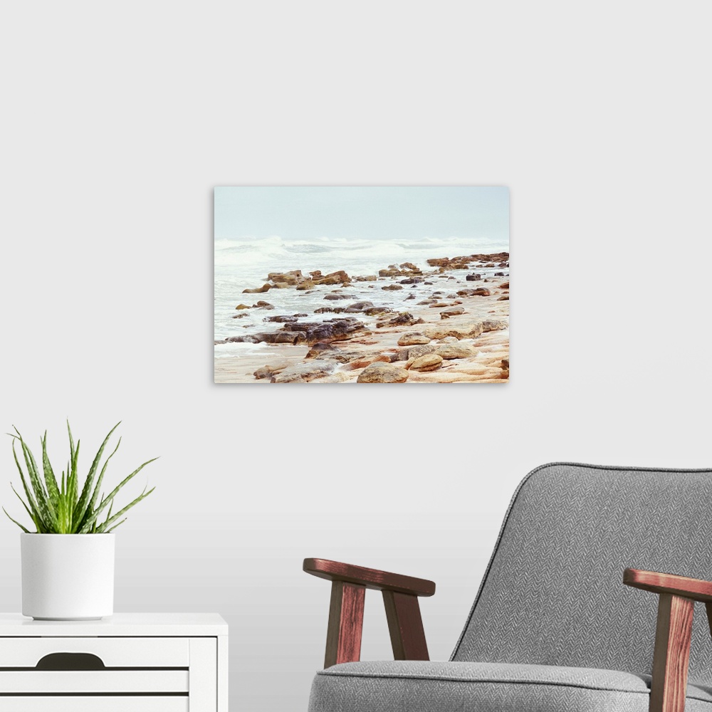 A modern room featuring A photograph of a rocky beach shore.