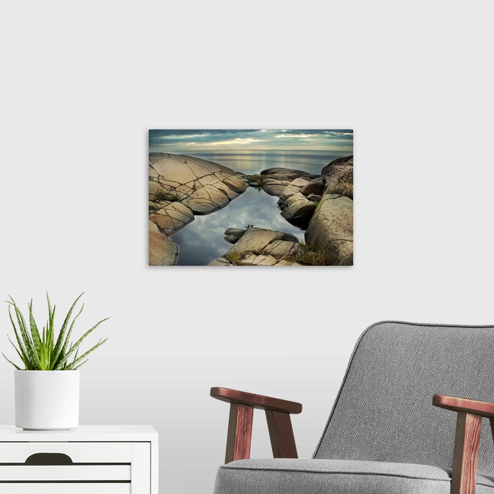 A modern room featuring A rocky shore with calm sea and rock pool