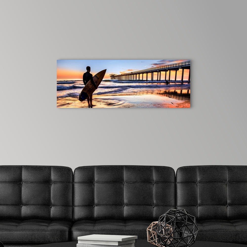 A modern room featuring Silhouetted panoramic photograph of a man holding a surf board on the shore of Scripps Beach in S...