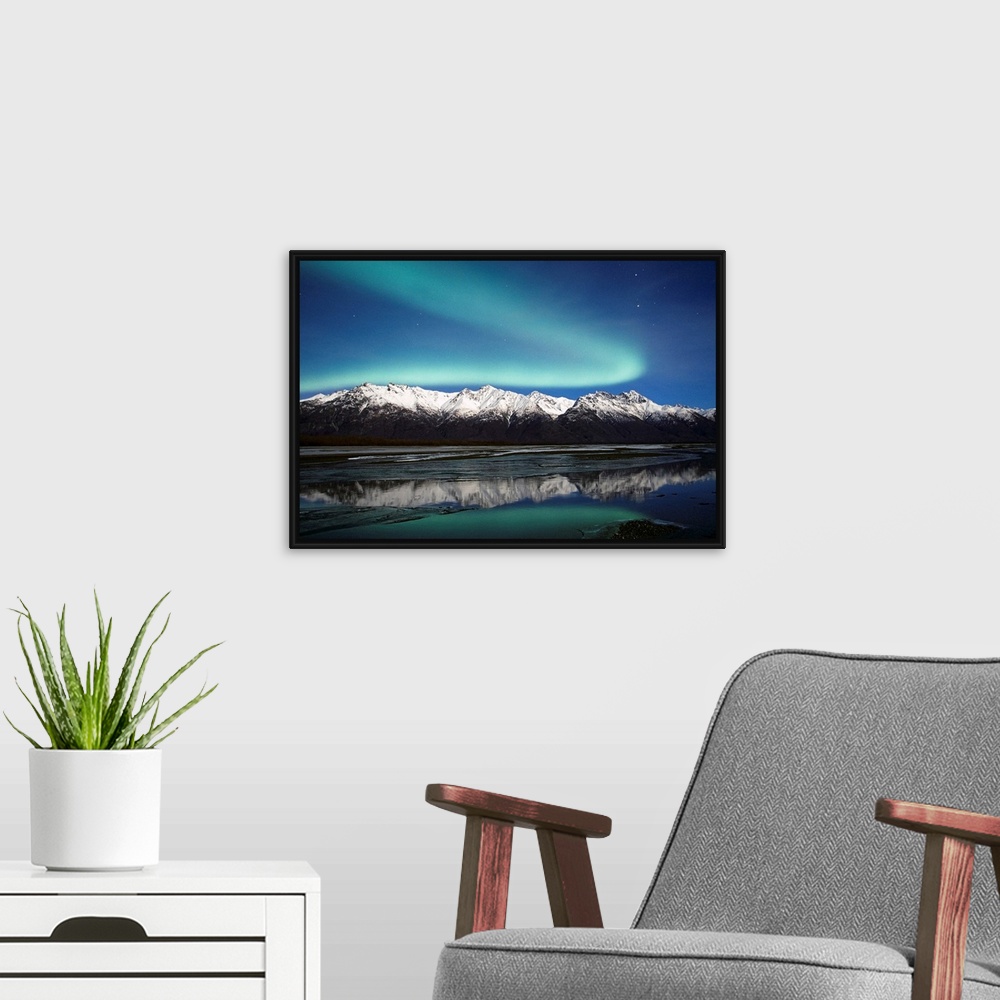 A modern room featuring A landscape photograph of the aurora borealis and mountains reflecting in a lake filled with ice.