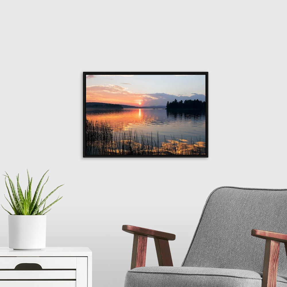 A modern room featuring Canvas print of a peaceful lake with a sunset reflected onto it.