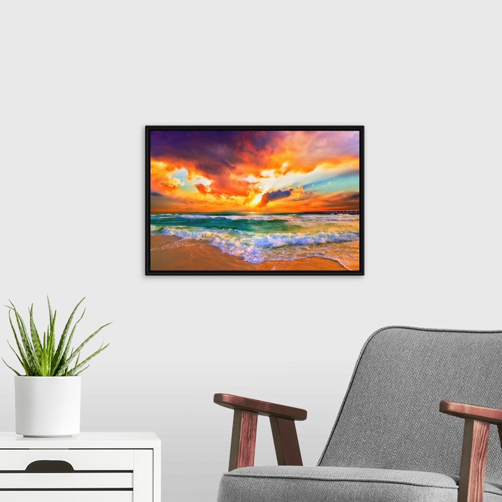 A modern room featuring A red, orange and purple sunset on the beach. Beautiful ocean waves roll onto the sea shore.