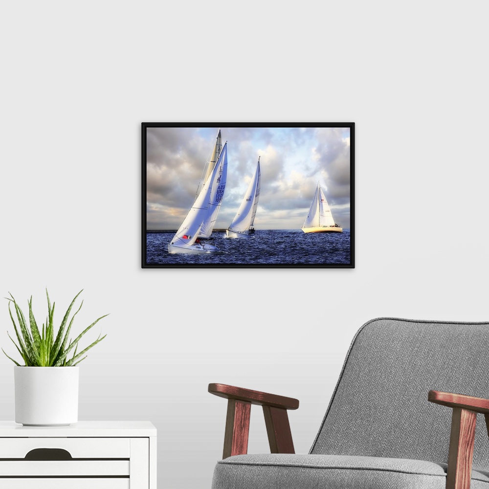 A modern room featuring Several sail boats are pictured in open water and the sky filled with grey clouds.