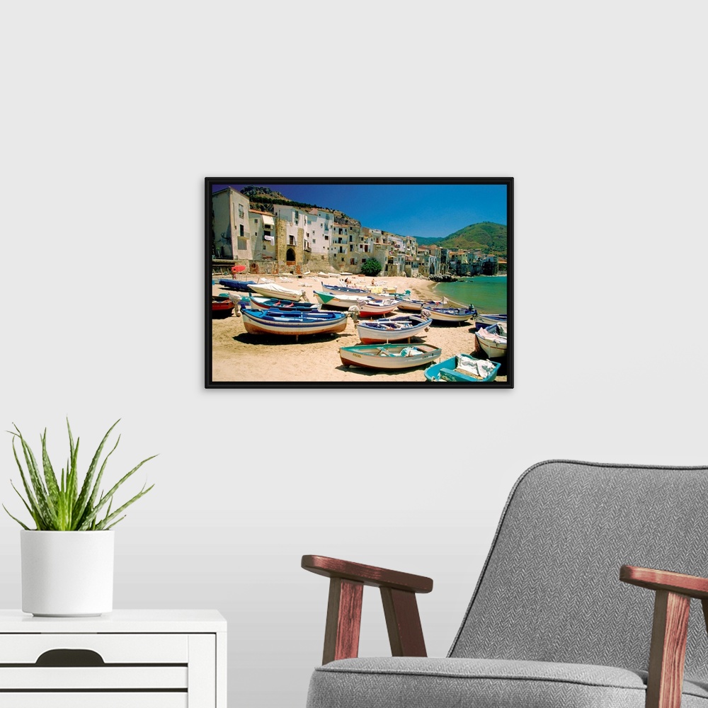A modern room featuring Huge photograph showcases a fleet of small water vessels sitting on top of a sandy beach within t...