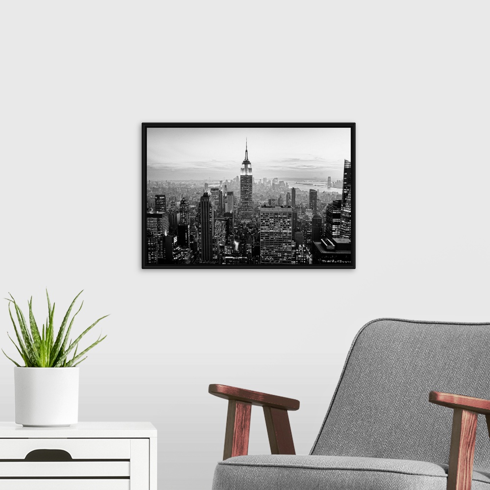 A modern room featuring High angled photograph of city buildings at dusk.  The building windows are filled with light cre...