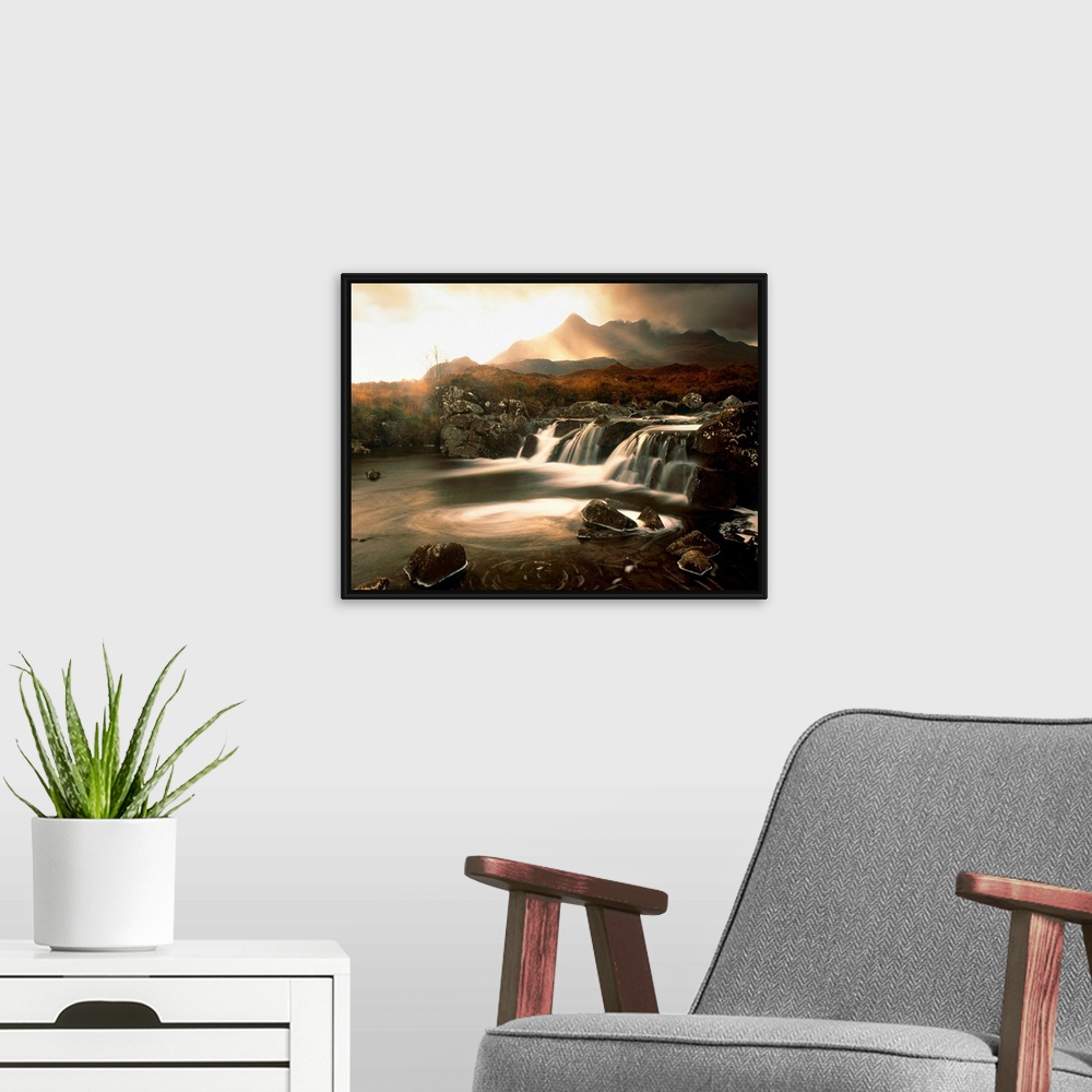 A modern room featuring Time lapsed photograph of water flowing through a rocky river while the sun glows behind clouds i...