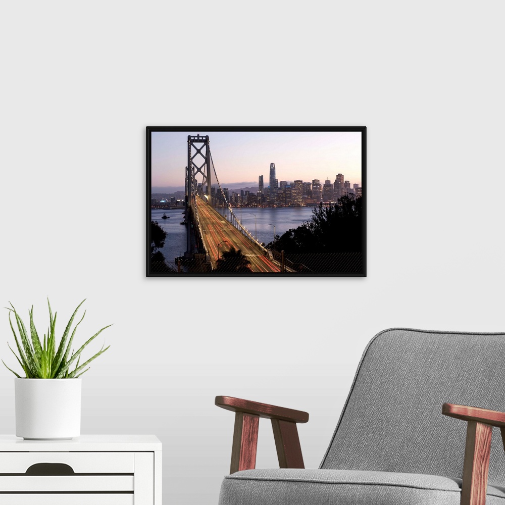 A modern room featuring Photograph of the Bay Bridge with a pink and purple sunset and the San Francisco skyline lit up i...