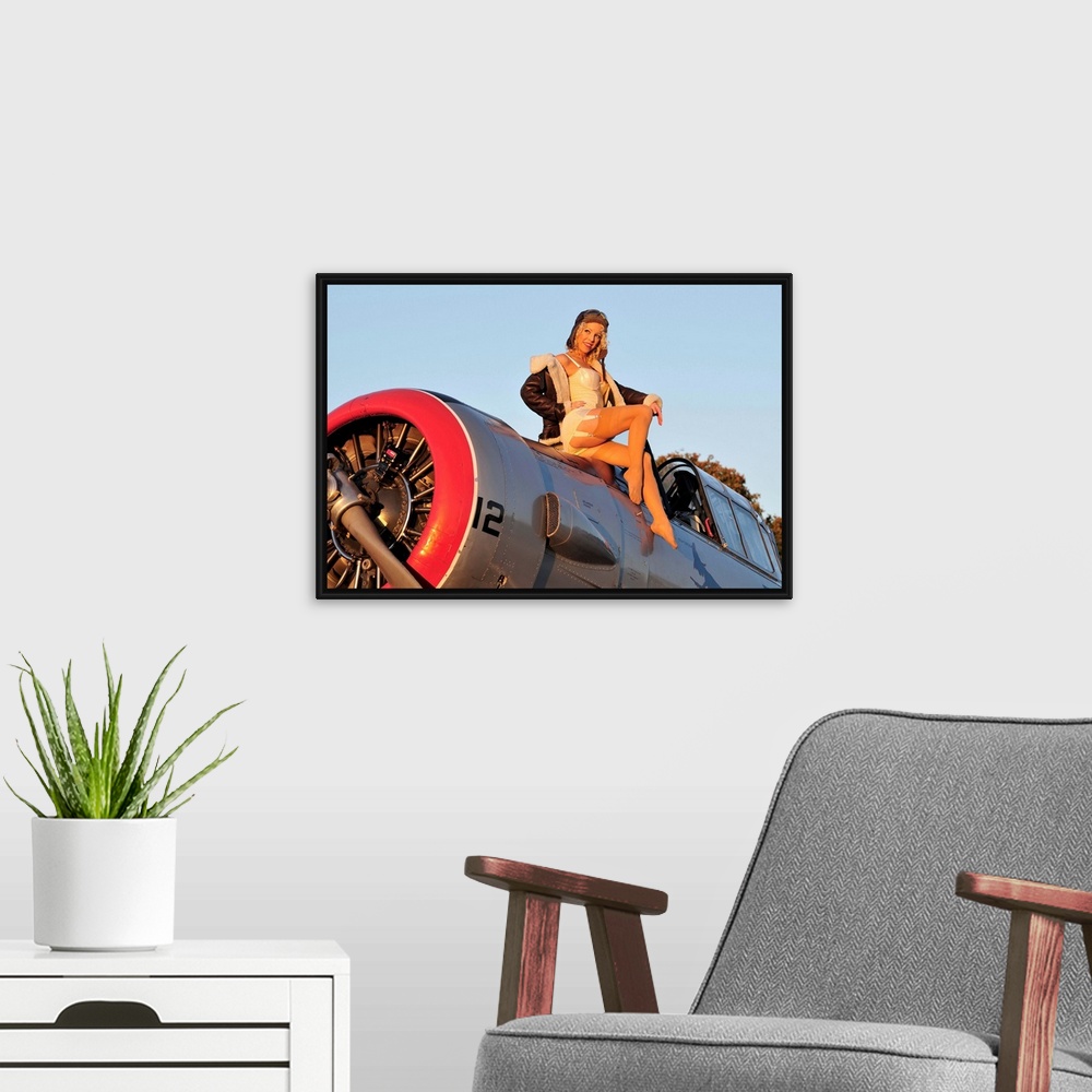 A modern room featuring 1940's style aviator pin-up girl posing with a vintage World War II T-6 Texan aircraft.