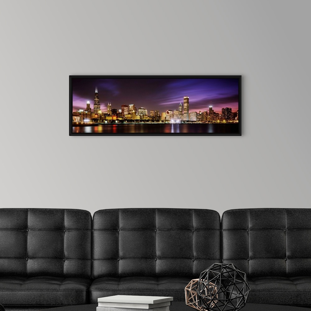 A modern room featuring A big cityscape panoramic of downtown Chicagoos lights reflecting off Lake Michigan at night.