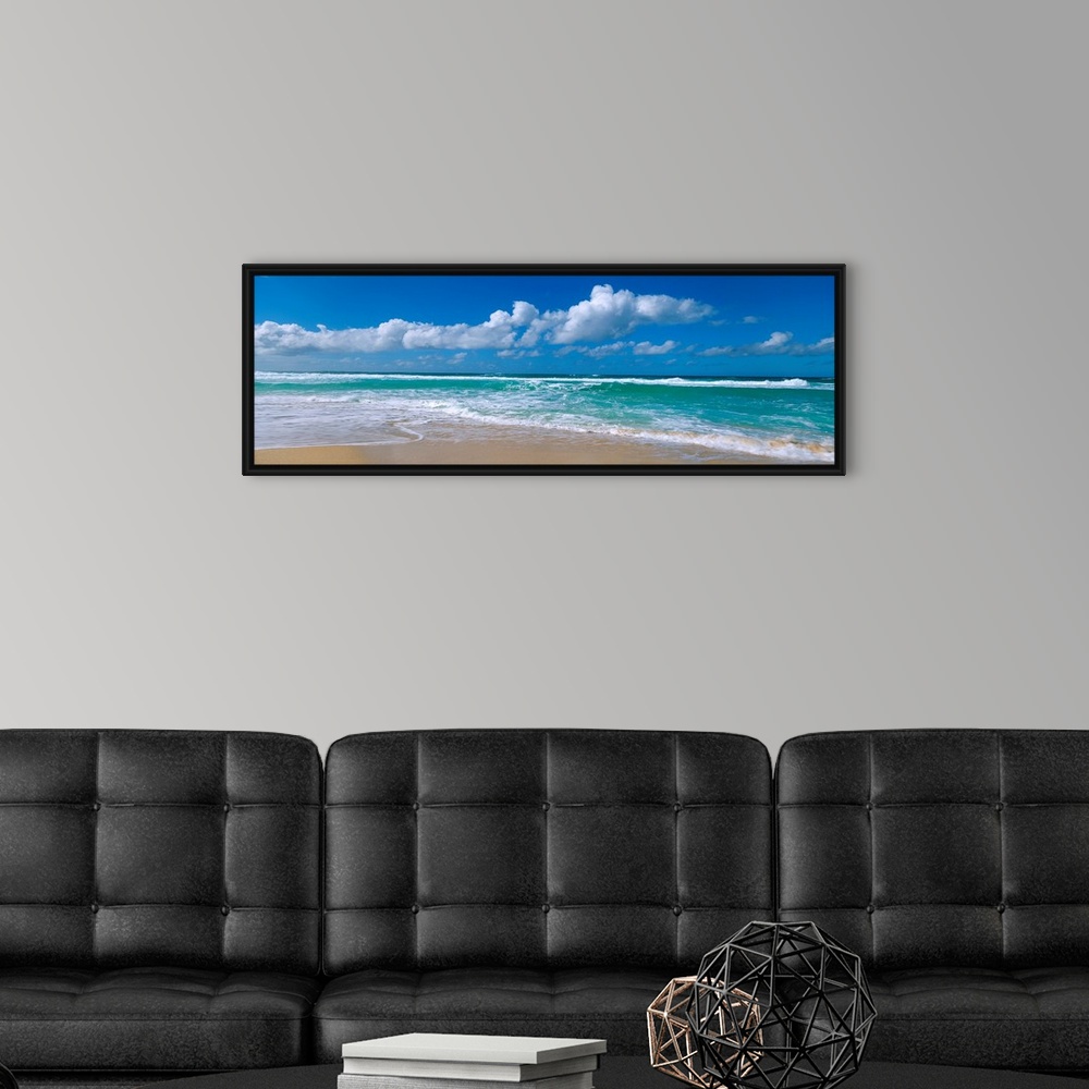 A modern room featuring Panoramic view of a Hawaiian beach where waves are washing up on the shore while the wind blows c...