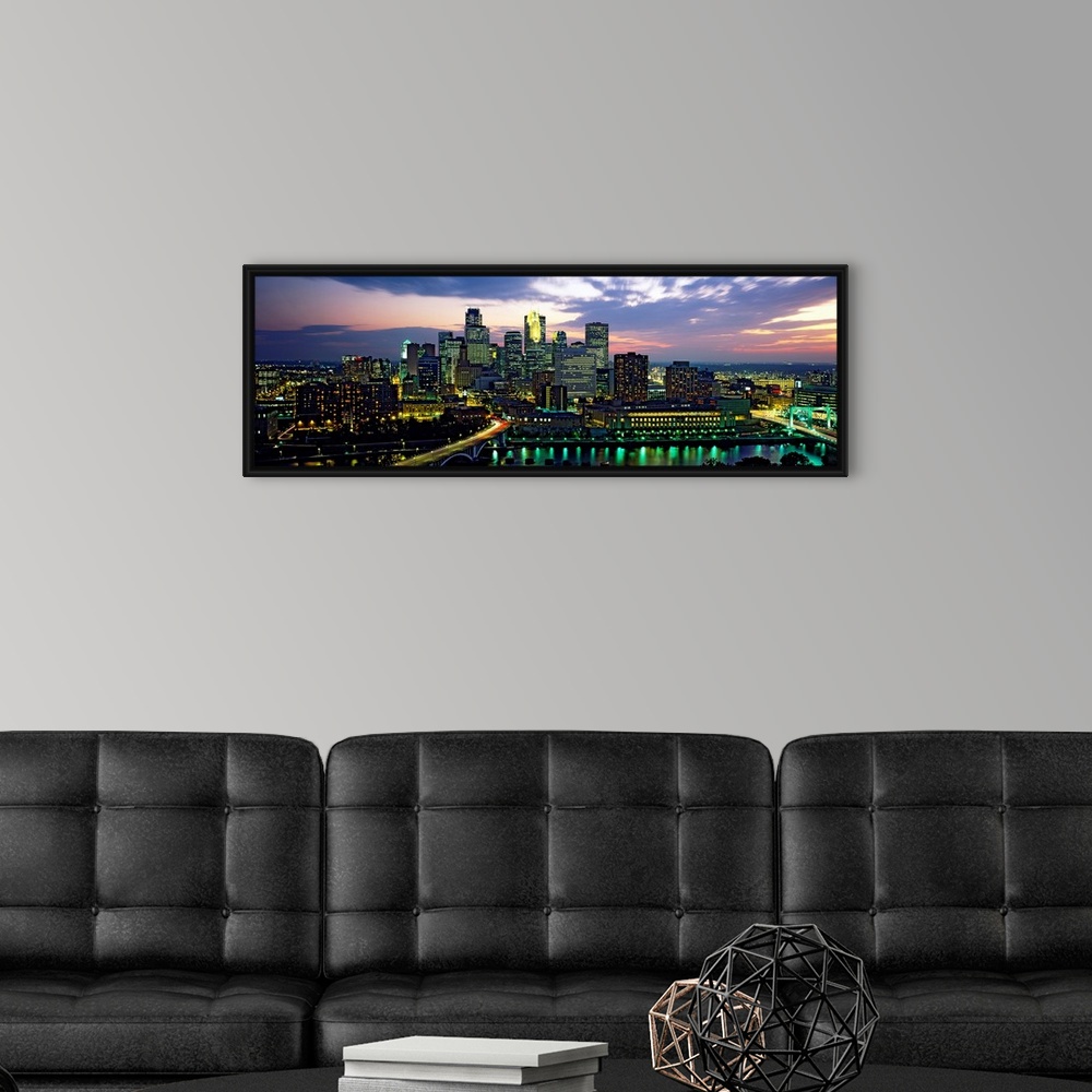A modern room featuring Wide angle panoramic photograph of Minneapolis skyscrapers at night, beneath a colorful sunset.