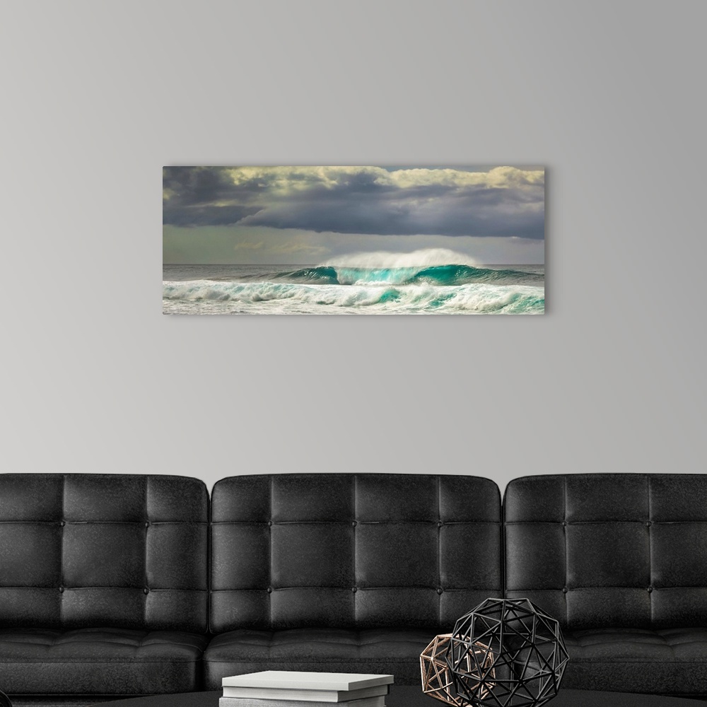 A modern room featuring Panoramic image of crashing ocean waves with large clouds above.