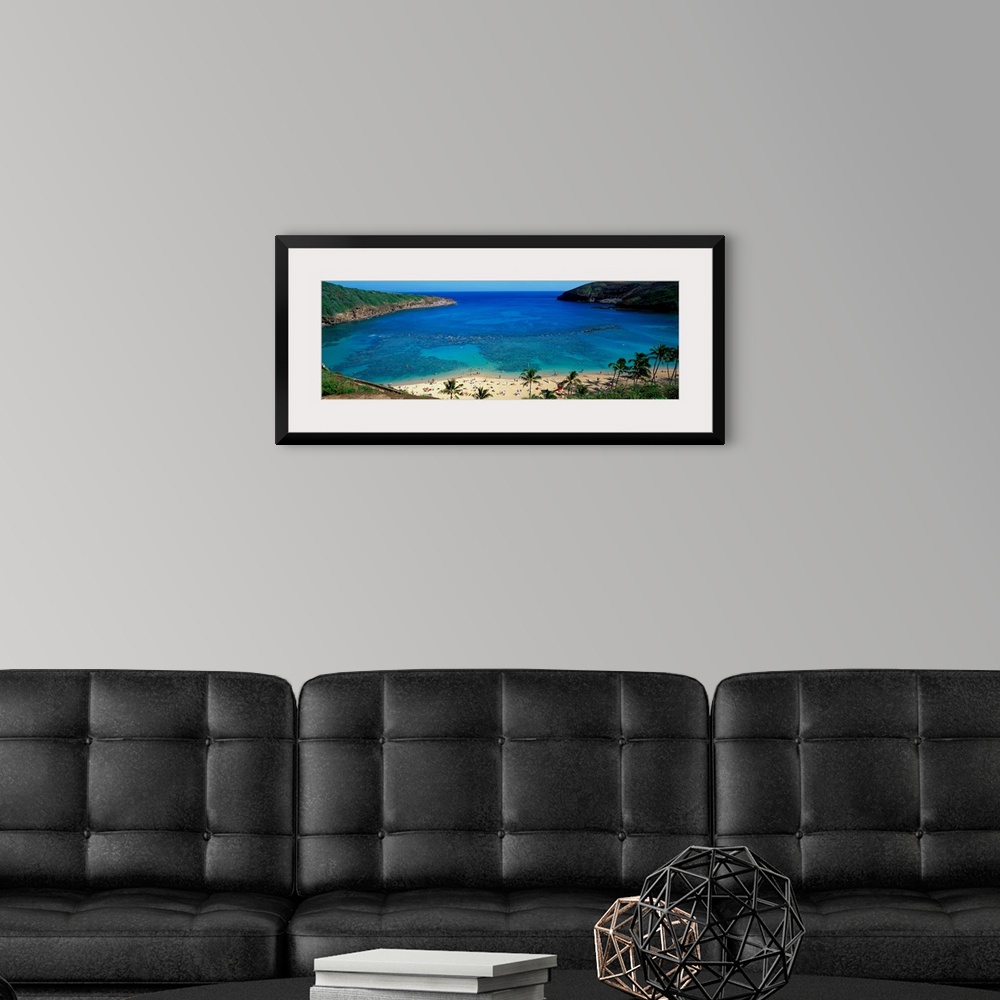 A modern room featuring High angle panoramic of a harbor on a tropical island and tourist sunbathing on the shore.