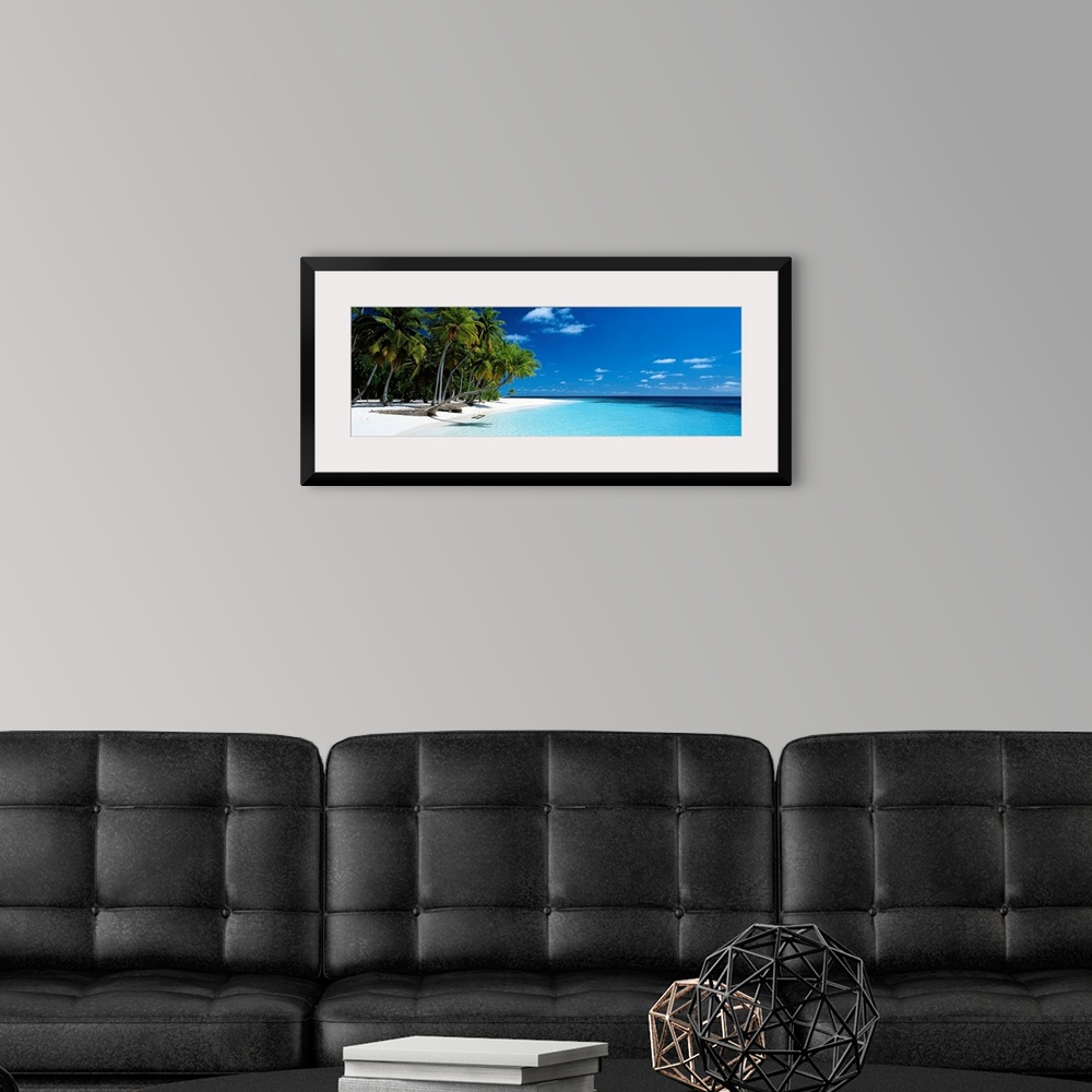 A modern room featuring Panoramic photograph of a vibrant beach on a sunny day in Maldives.  The tall palm trees run acro...