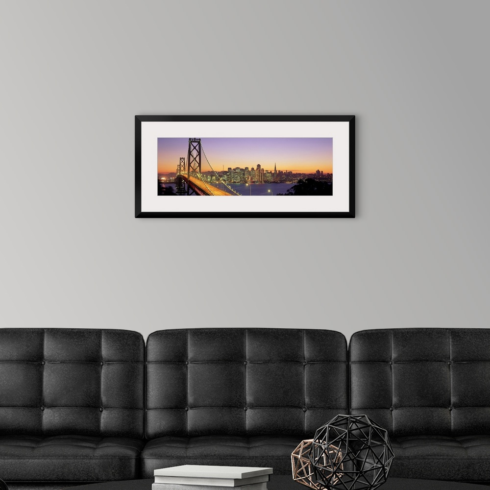 A modern room featuring Twilight and the Golden Gate Bridge with the San Francisco Skyline with a purple and gold sky.