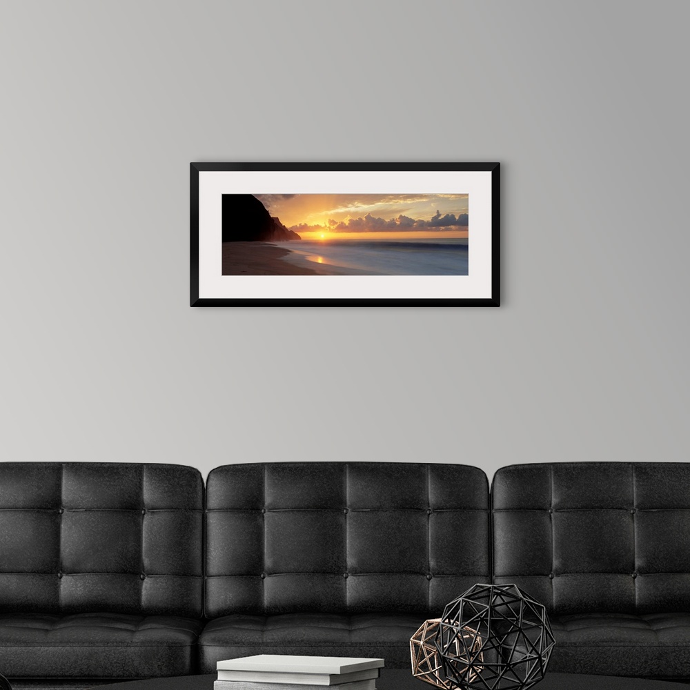 A modern room featuring The sun sinks below the horizon viewed from the beach on a tropical Pacific island.
