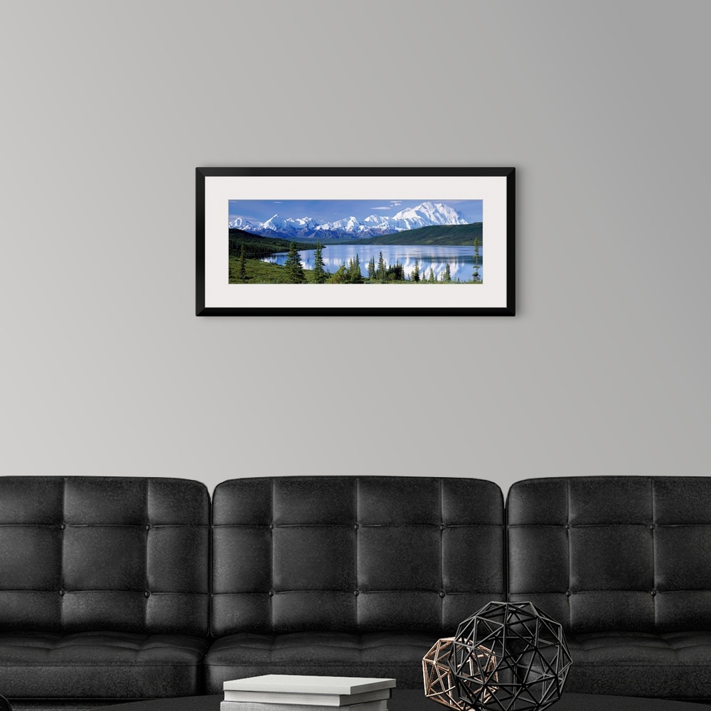 A modern room featuring Panoramic photograph shows a landscape filled with trees as they surround and reflect into a lake...