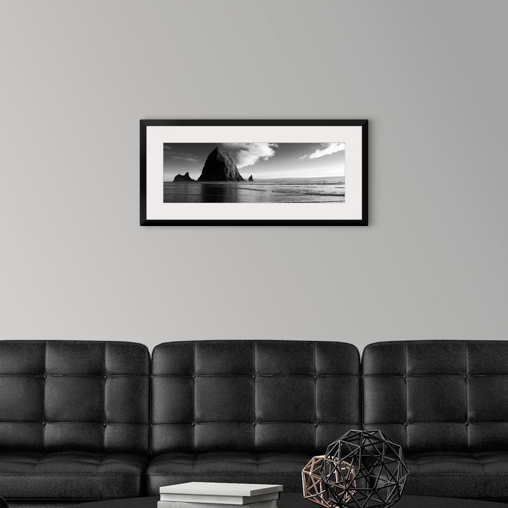 A modern room featuring Black and white panoramic photograph of Haystack Rock with rippling waters.