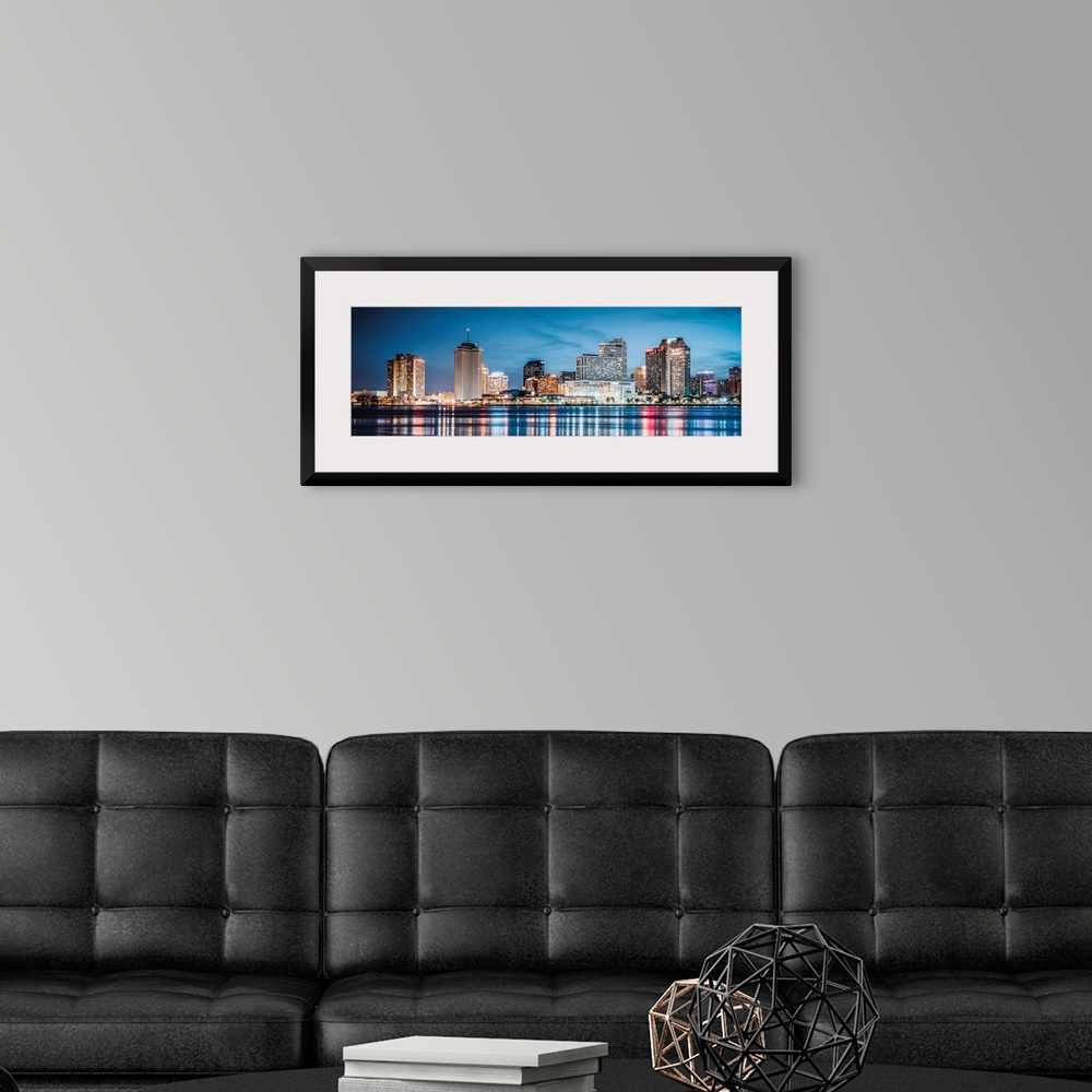 A modern room featuring Panoramic photograph of the New Orleans skyline lit up at dusk and reflecting colorful bands onto...