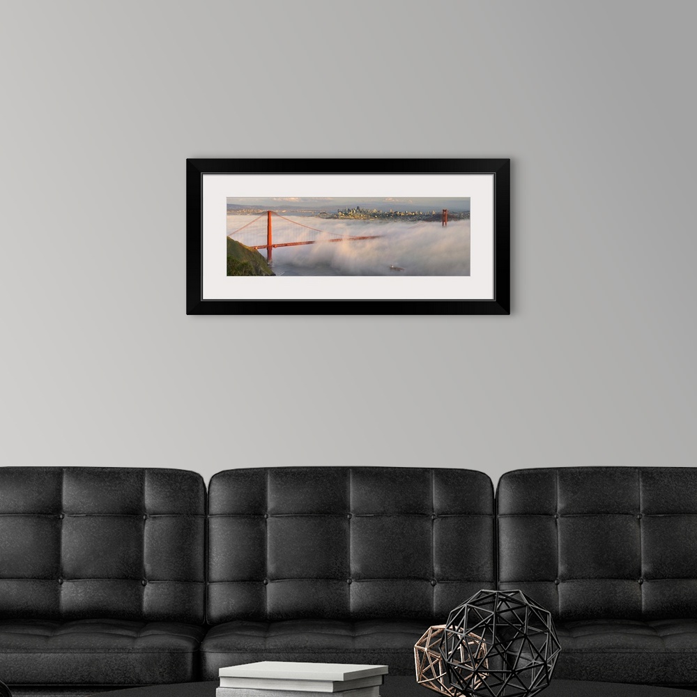A modern room featuring Panoramic photograph of the foggy Golden Gate Bridge in San Fransisco with the skyline in the bac...