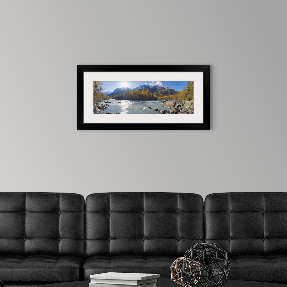A modern room featuring A photograph of a river running through the Alaskan landscape in lined with trees on a sunny day ...