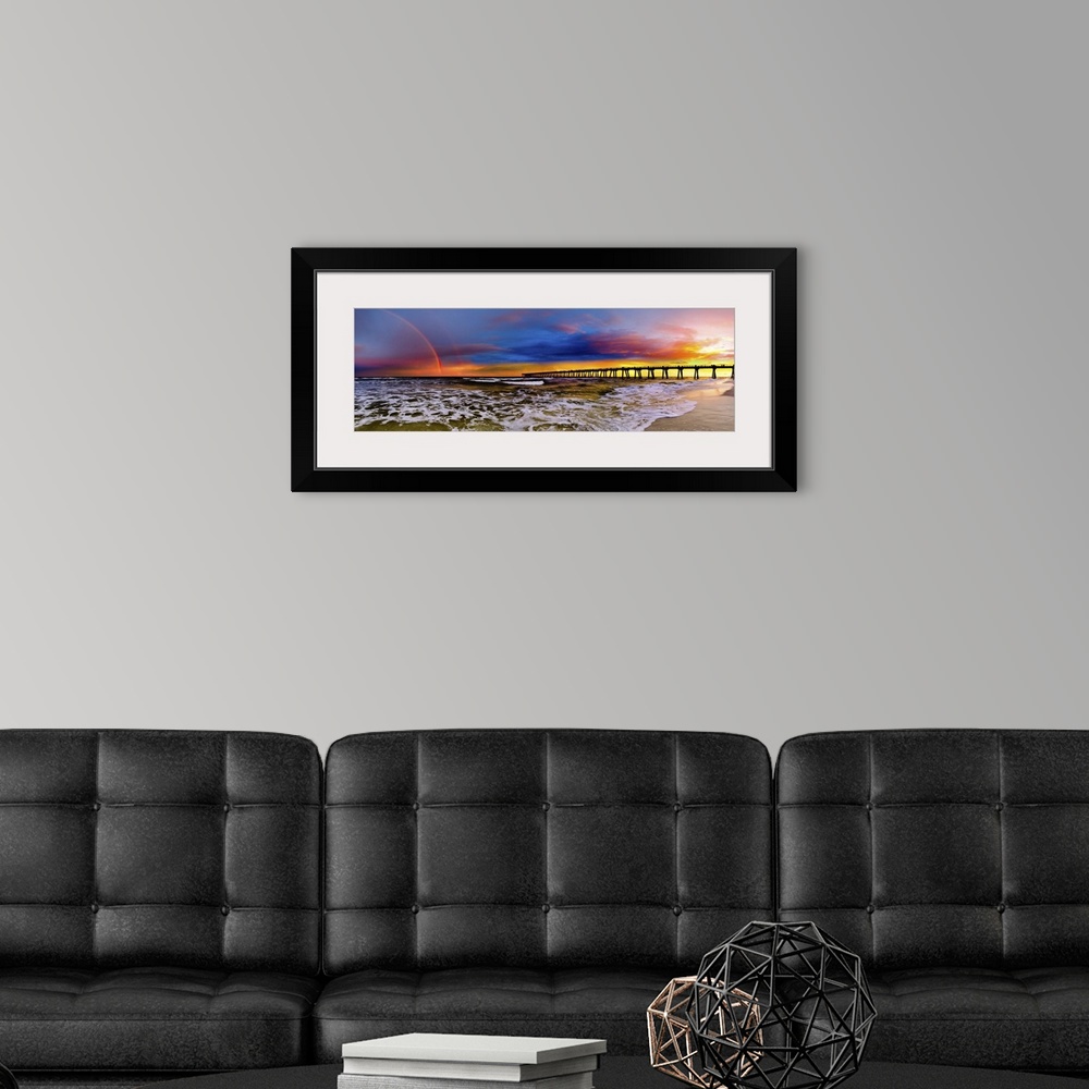 A modern room featuring A dark blue sky with a purple sunset featuring a full rainbow. A long pier can be seen reaching i...