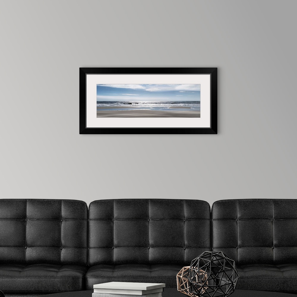 A modern room featuring A panoramic photo illustrating a tranquil view of the beach as the sun shimmers on the sea.