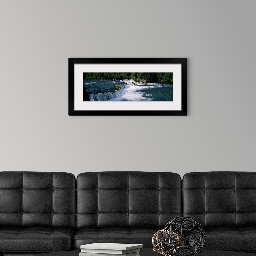 A modern room featuring This large panoramic piece shows bears fishing in water and some about to jump down a small water...