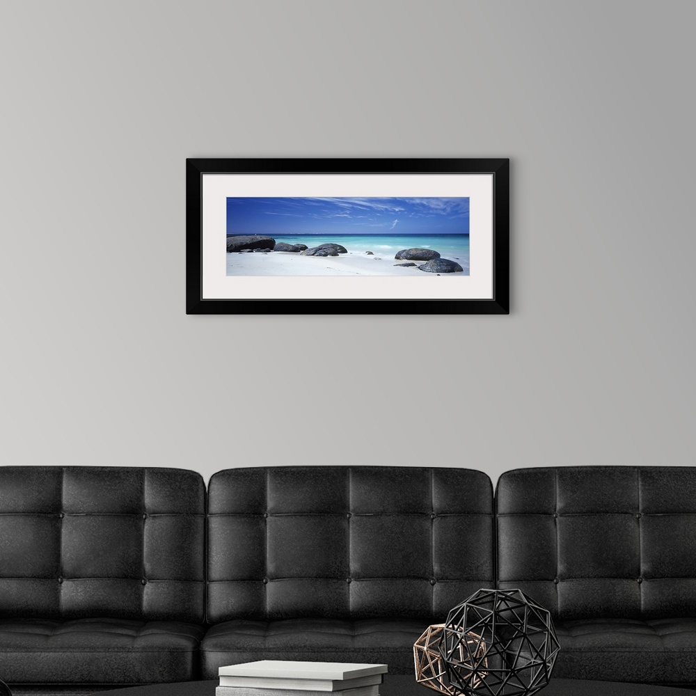 A modern room featuring Wide angle photograph on a large canvas of big rocks on a white sand beach near the crystal blue ...
